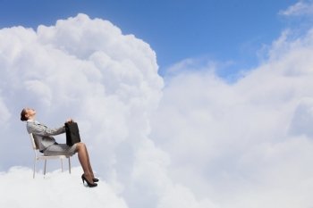 Businesswoman on cloud. Young businesswoman sitting on cloud high in sky