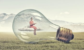 Inside of idea bulb. Young woman sitting on cloud inside of glass light bulb with book in hands