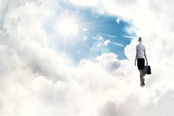 Success in business. Back view of businesswoman standing on cloud high in sky