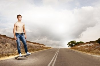 Teenager on skateboard. Young skater in jeans riding on road