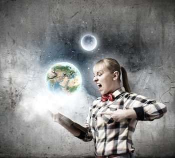 Reading concept. Woman in casual wear holding opened book in hands. Elements of this image are furnished by NASA