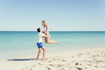 Happy couple  jumping on beach vacations. Travel concept of young couple cheering for summer holidays on beach