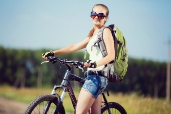 Your active lifestyle position. Young sporty girl with backpack riding bicycle along roadside