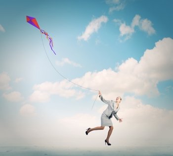 Business break. Young happy businesswoman running with colorful kite