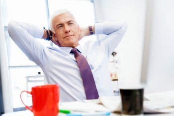 Businessman in office relaxing leaning back on chair. Few minutes to relax