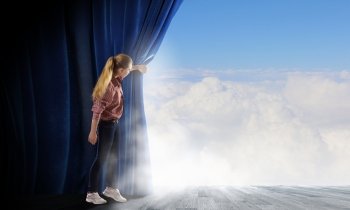 Woman looking out from curtain. Young woman in casual opening blue curtain and looking at clear sky