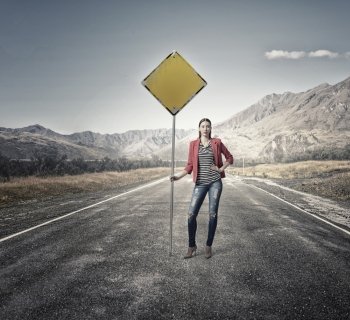 Pretty girl on asphalt road. Young girl in red jacket on road showing roadsign 