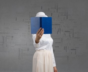 Woman hiding face behind book. Woman in white with opened book against her face