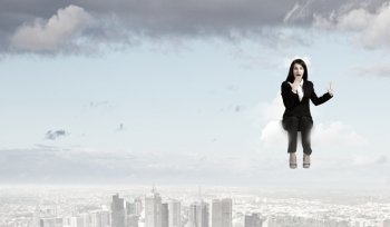 Surprised businesswoman. Young emotional businesswoman sitting on cloud above city