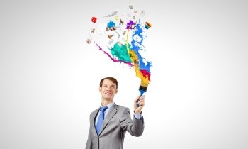 Young businessman holding paint brush with colorful splashes