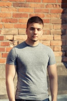 Portrait of handsome young muscular man in front of brick wall