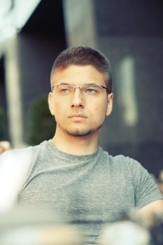 Young man wearing eyeglasses in outdoor restaurant 
