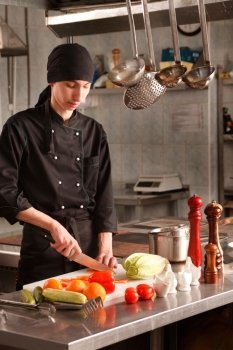 Young cook preparing salad in restaurant kitchen