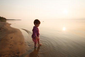 Little baby near the lake on sunset
