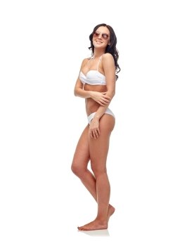 people, fashion, swimwear, summer and beach concept - happy young woman in sunglasses and white swimsuit