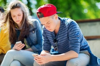 technology, internet addiction and people concept - teenage friends with smartphones outdoors