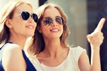 summer, fashion, accessories and people concept - happy women in sunglasses pointing finger in city