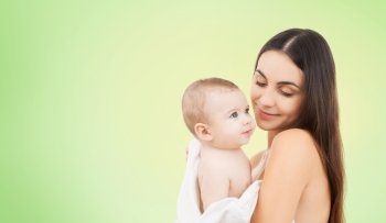 family, motherhood, parenting, people and child care concept - happy mother holding adorable baby over green background