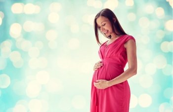 pregnancy, motherhood, people and expectation concept - happy pregnant woman with big tummy over blue holidays lights background