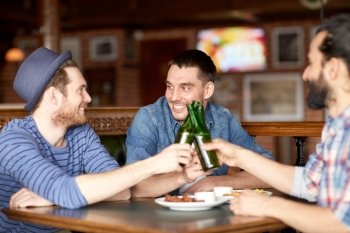 people, leisure, friendship and party concept - happy male friends drinking bottled beer at bar or pub and clinking bottles