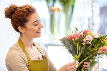 people, business, sale and floristry concept - happy smiling florist woman making bunch at flower shop