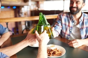 people, men, leisure, friendship and celebration concept - happy male friends drinking beer and clinking bottles at bar or pub