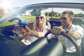 road trip, travel, summer vacation, technology and people concept - happy man and woman driving car and using gps navigator in cabriolet car