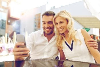 love, date, technology, people and relations concept - smiling happy couple taking selfie with smatphone at restaurant terrace