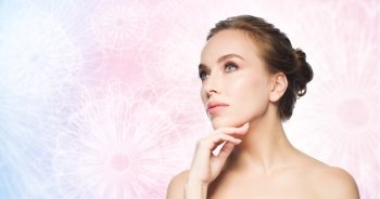 beauty, people and bodycare concept - beautiful young woman touching her face over pink patterned background