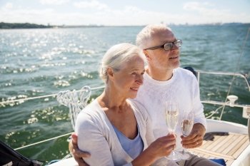 sailing, age, tourism, travel and people concept - happy senior couple drinking champagne on sail boat or yacht deck floating in sea