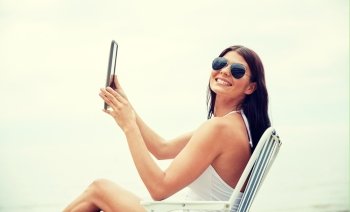 summer vacation, tourism, travel, holidays and people concept - smiling young woman with tablet pc computer sunbathing in lounge or folding chair on beach