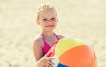 summer, childhood, vacation and people concept - happy little girl playing with inflatable ball on beach