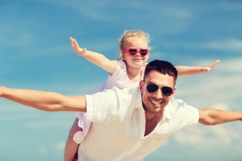 family, travel, vacation, adoption and people concept - happy man and little girl in sunglasses having fun over blue sky background