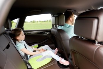 family, transport, road trip and people concept - happy little girl in safety seat driving in car with her dad