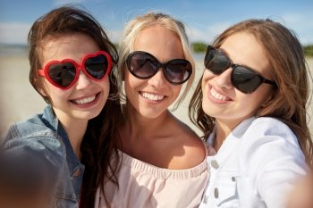summer vacation, holidays, travel and people concept- group of smiling young women taking selfie on beach