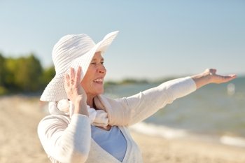 age, leisure, travel, tourism and people concept - happy senior woman in sun hat on summer beach