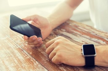 business, technology and people concept - close up of male hand holding smart phone and wearing watch at home