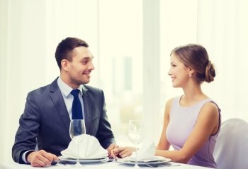 restaurant, couple and holiday concept - smiling couple looking at each other at restaurant. smiling couple looking at each other at restaurant