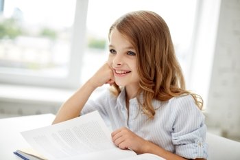education, people, children and learning concept - happy student girl reading book at school