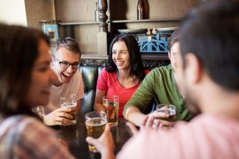 people, leisure, friendship and communication concept - happy friends drinking beer and talking at bar or pub