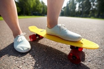 skateboarding, leisure, extreme sport and people concept - close up of teenage girl legs riding short modern cruiser skateboard on road. close up of female feet riding short skateboard