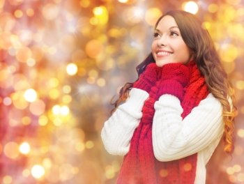 winter, people, christmas and holidays concept - happy smiling woman in scarf and mittens over lights background