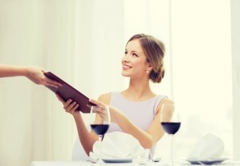 reastaurant and happiness concept - smiling young woman giving menu to waiter at restaurant. smiling woman giving menu to waiter at restaurant