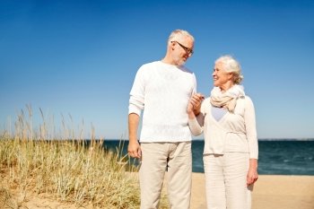 family, age, travel, tourism and people concept - happy senior couple holding hands and talking on summer beach