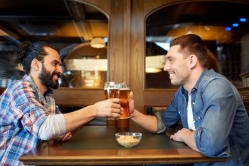 people, leisure, friendship and party concept - happy male friends drinking draft beer at bar or pub and clinking glasses