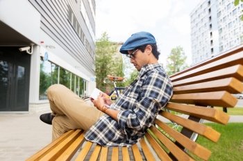 lifestyle, creativity, freelance, inspiration and people concept - creative man with notebook or diary writing sitting on city street bench