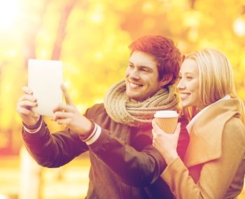 travel, tourism, modern technology, holidays and dating concept - couple taking photo picture with tablet pc camera in autumn park