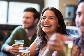 people, leisure, friendship, emotion and communication concept - happy woman with her friends drinking beer at bar or pub and laughing