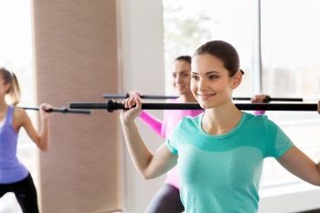 fitness, sport, training, people and lifestyle concept - group of happy women with bars exercising in gym