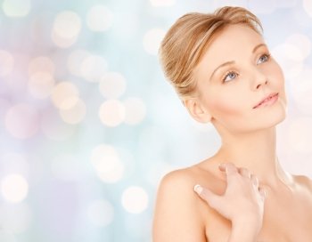 beauty, people and bodycare concept - beautiful young woman face and hands over blue holidays lights background